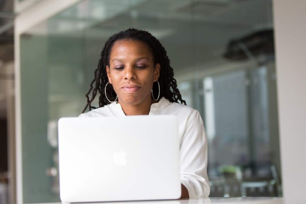 Woman wearing a white blouse types on her laptop.