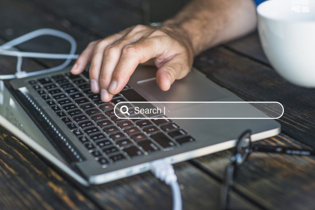 Search bar appears over an image of a mans hand on a laptop keyboard.