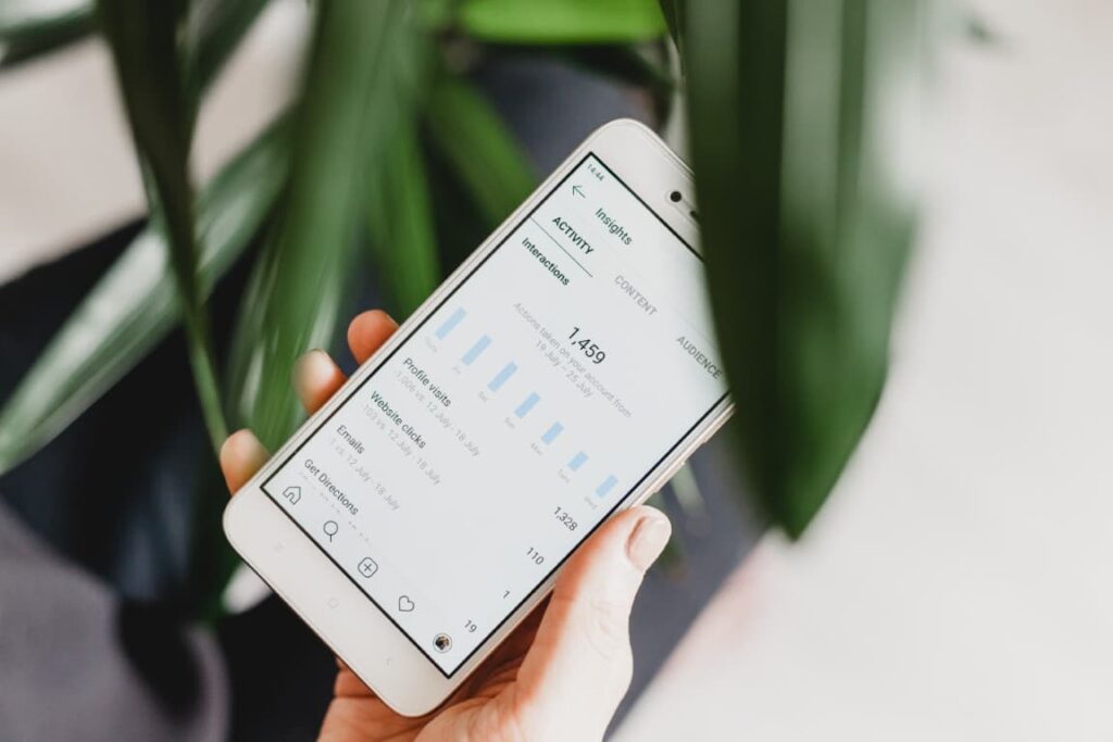 A hand holds a smartphone with social media insights displayed on the screen.