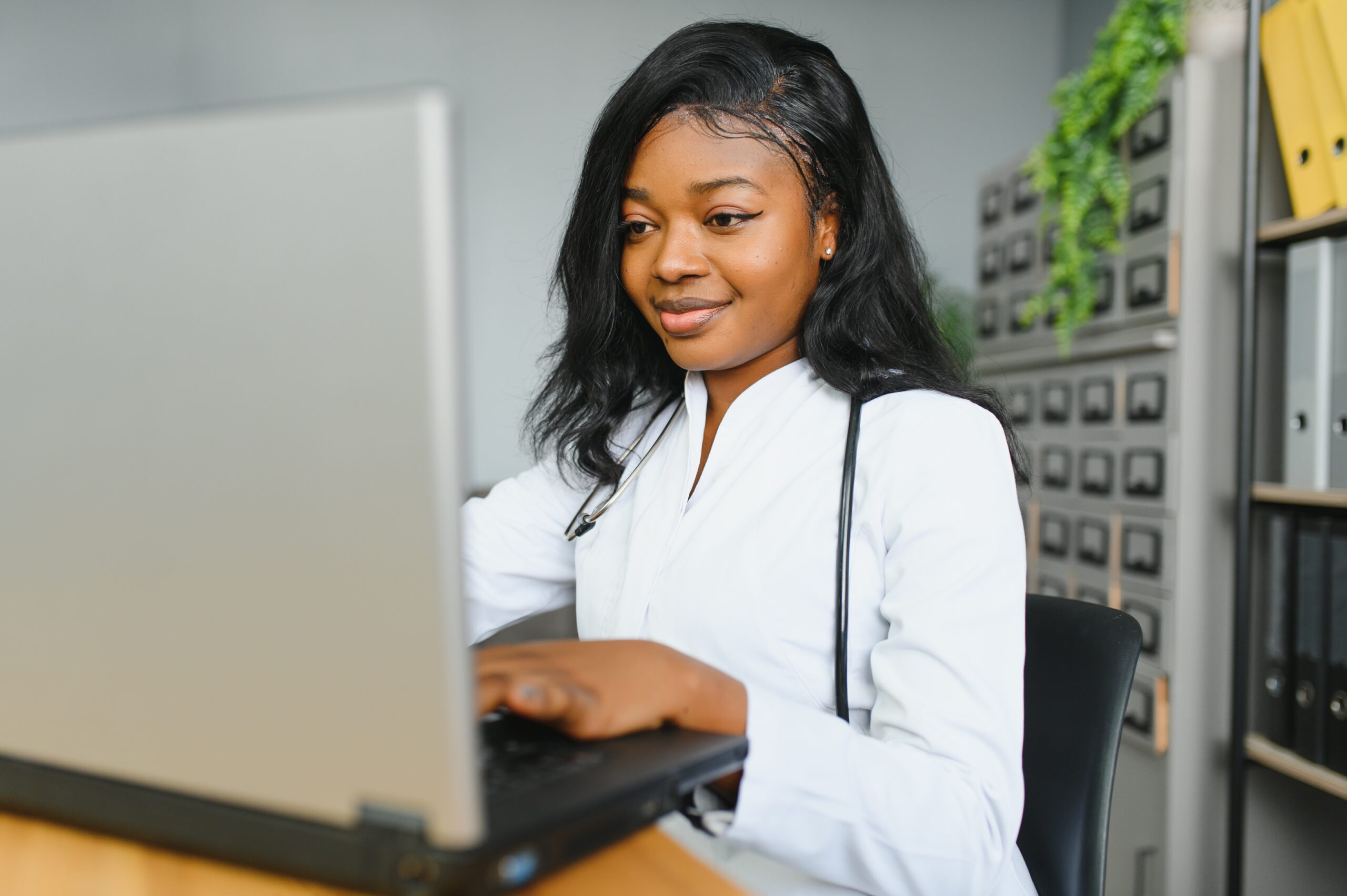 Important Meta Update, image of a happy female doctor wearing a white coat and stethoscope types on a laptop.