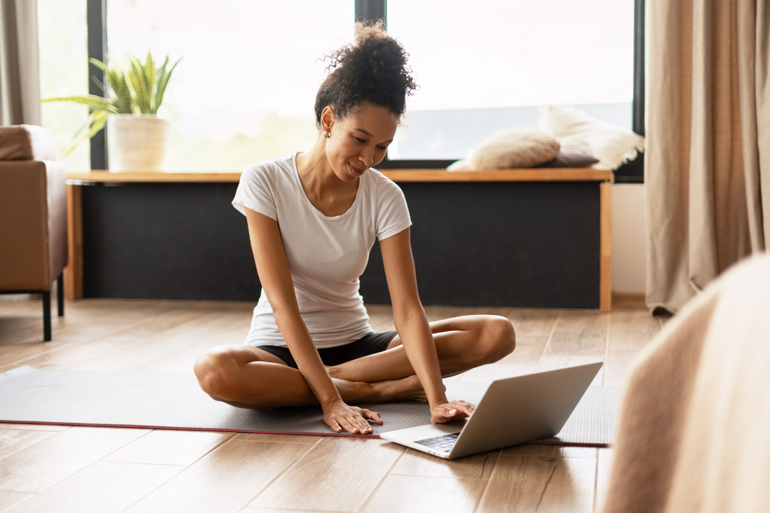 SEO for YouTube, image of a woman sitting on a yoga mat with her legs crossed and her laptop in front of her.