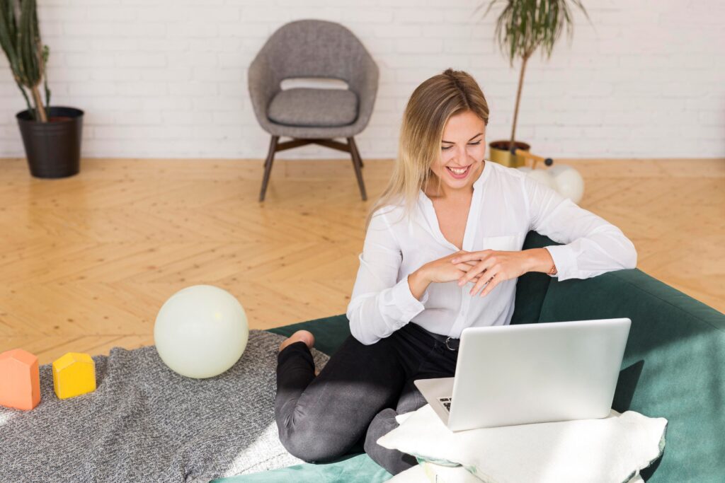 Three Things Your Clinic Can Do Right Now to Boost SEO, image of a happy woman lounging on a dark green couch, facing her open laptop.
