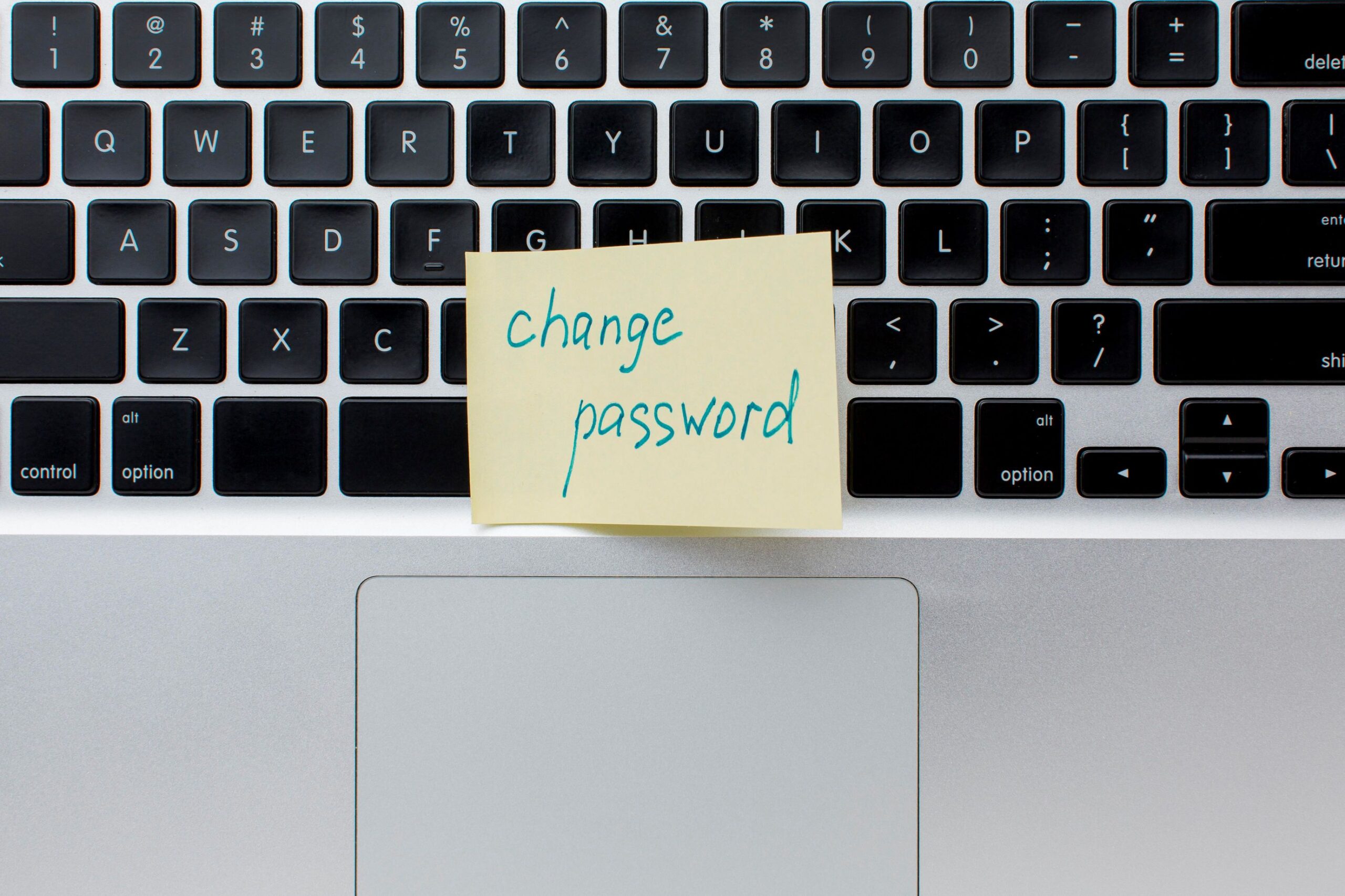 Defend Your WordPress, image of a computer keyboard with a yellow Post-it note on top that has a hand written note: “change password”.
