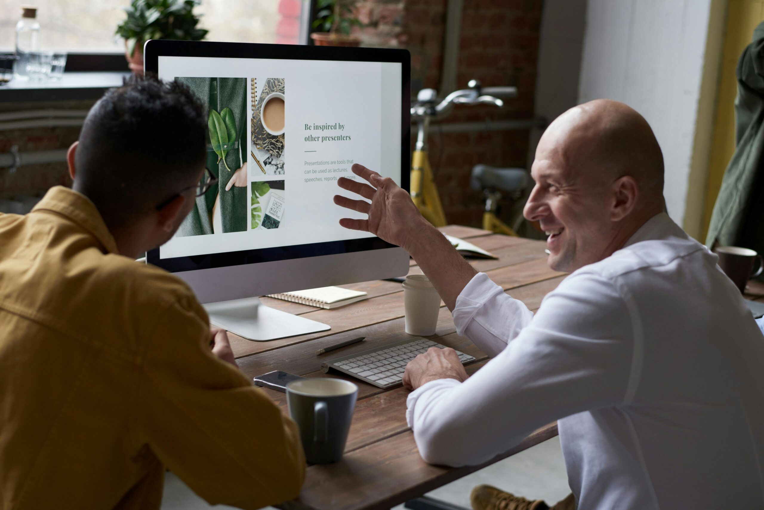 website disclaimer and privacy policy,, image of two men sitting at a wood table looking at a computer screen with a mug on the table between them.