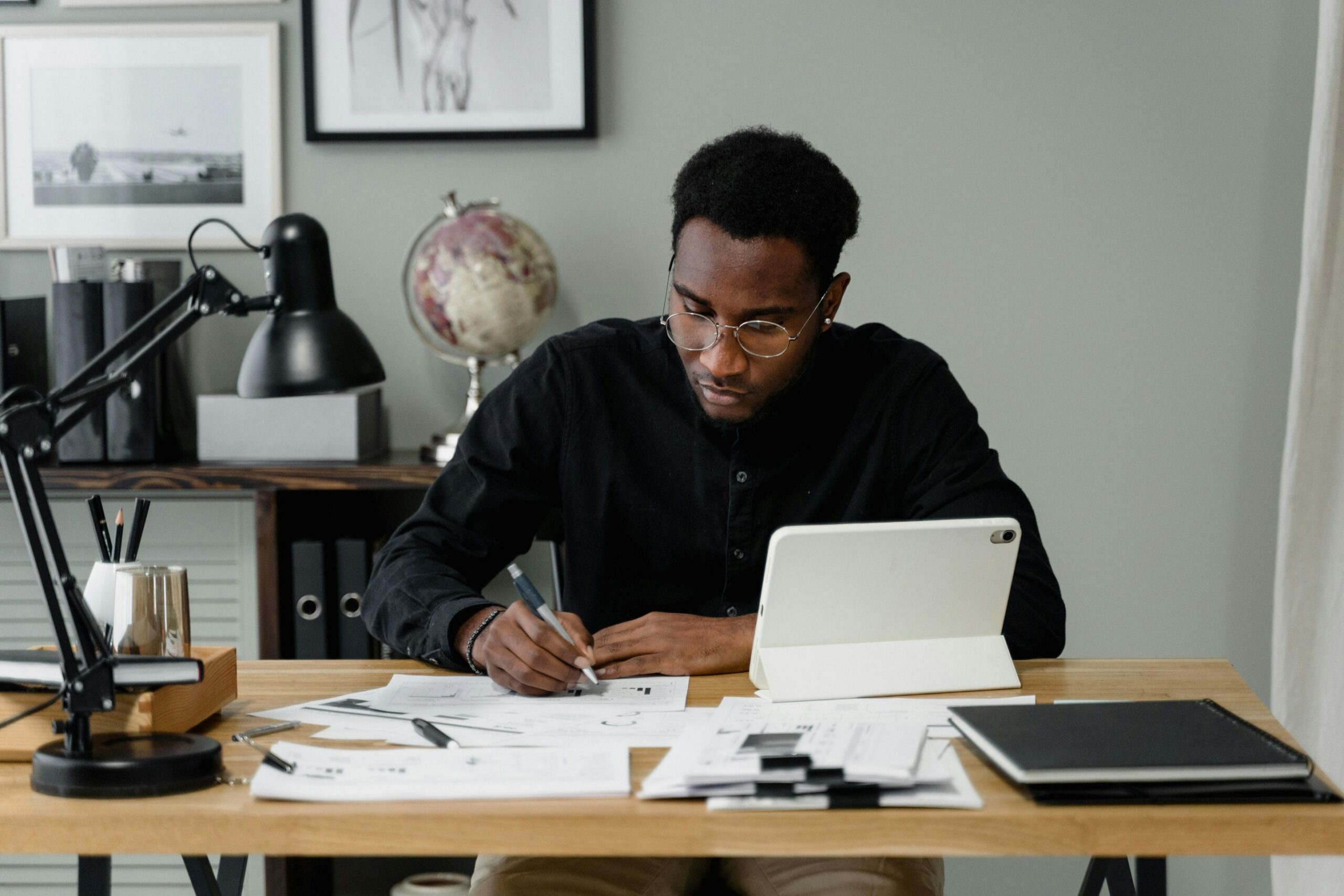 Optimizing your book on Amazon KDP, a man plans at a desk with a tablet and piles of paper.
