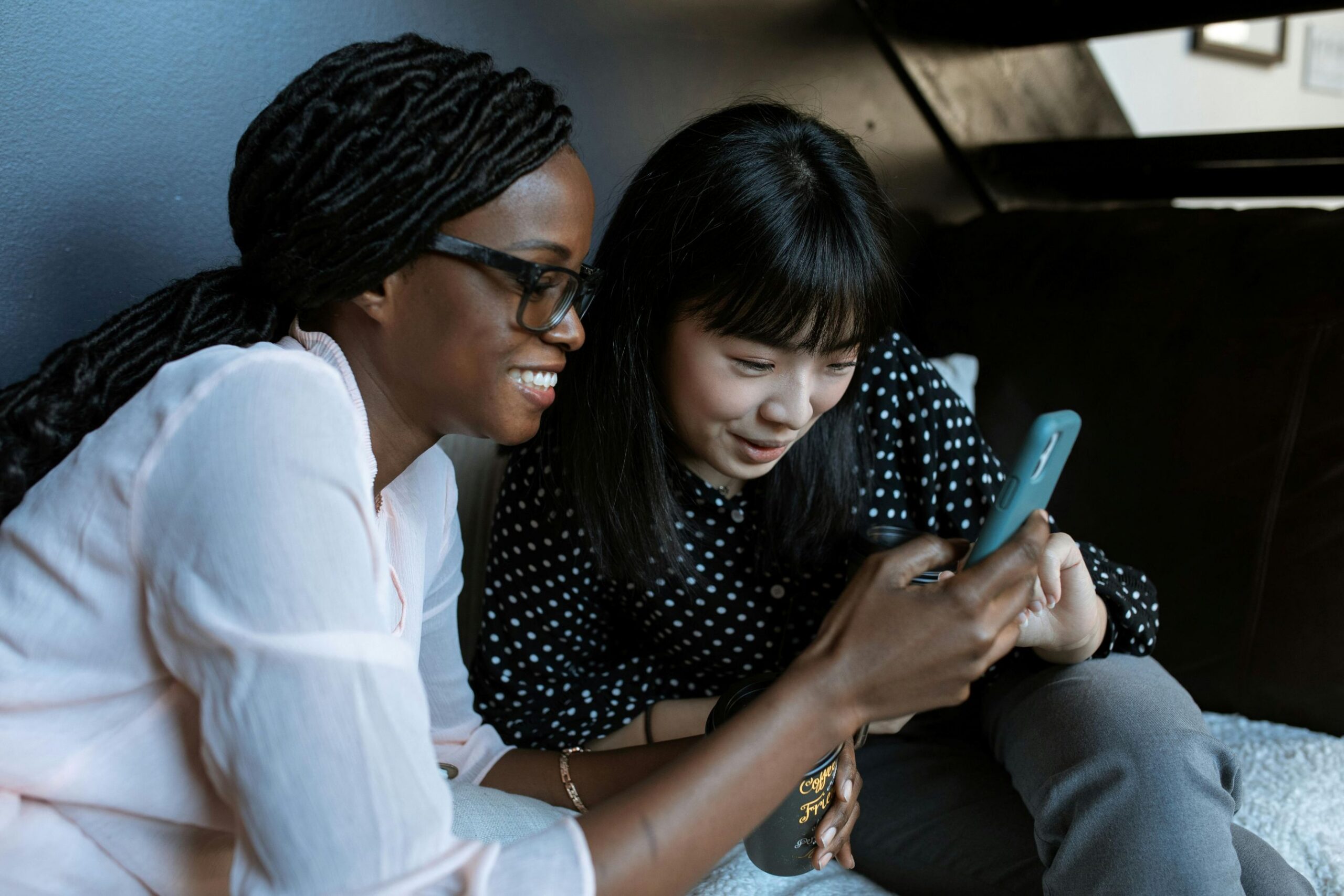 Optimizing your book on Amazon KDP, two women sitting and looking at a cellphone together.
