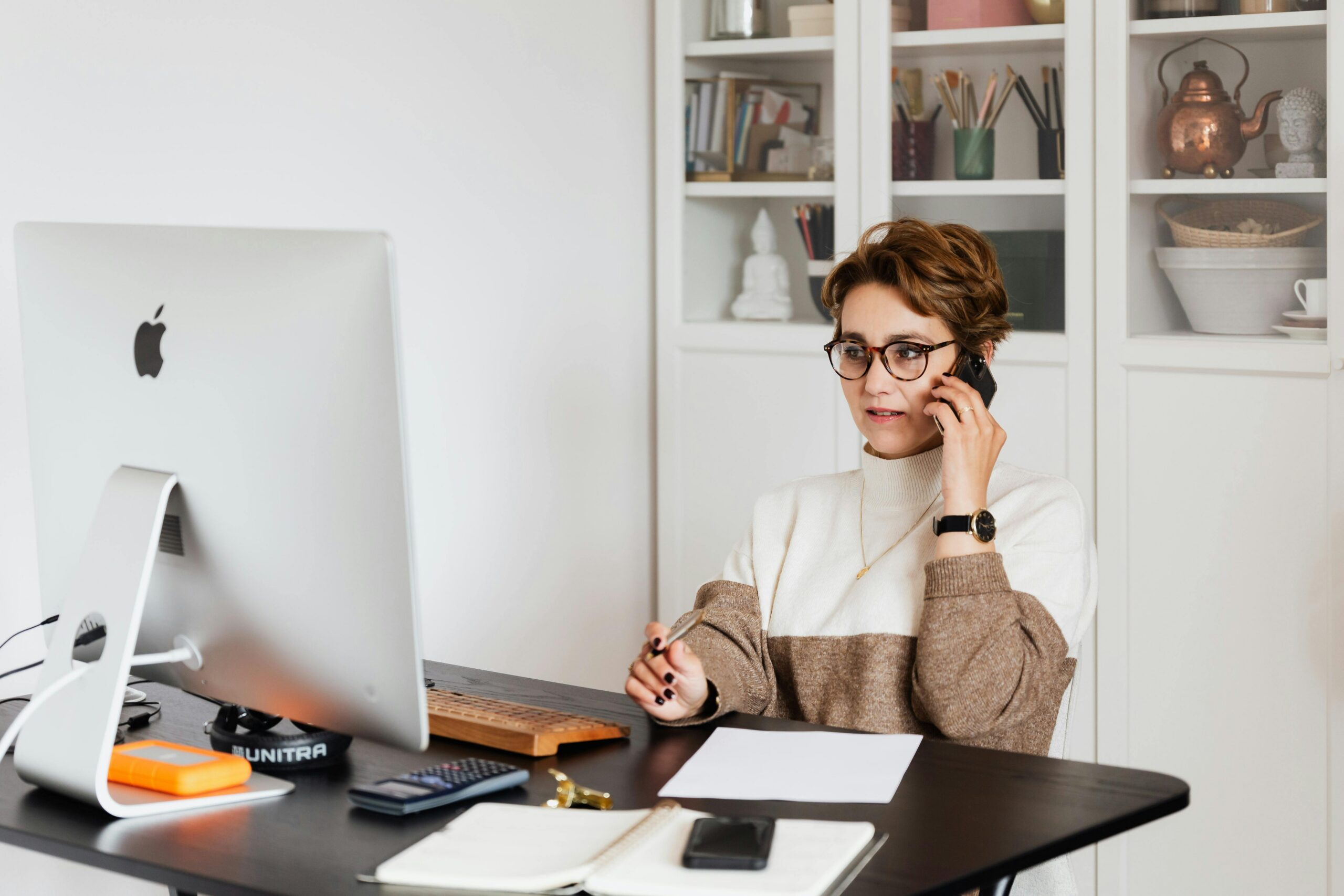 online reputation management, online therapy reviews, image of a woman sitting at a desk talking on her cellphone and looking at a computer.