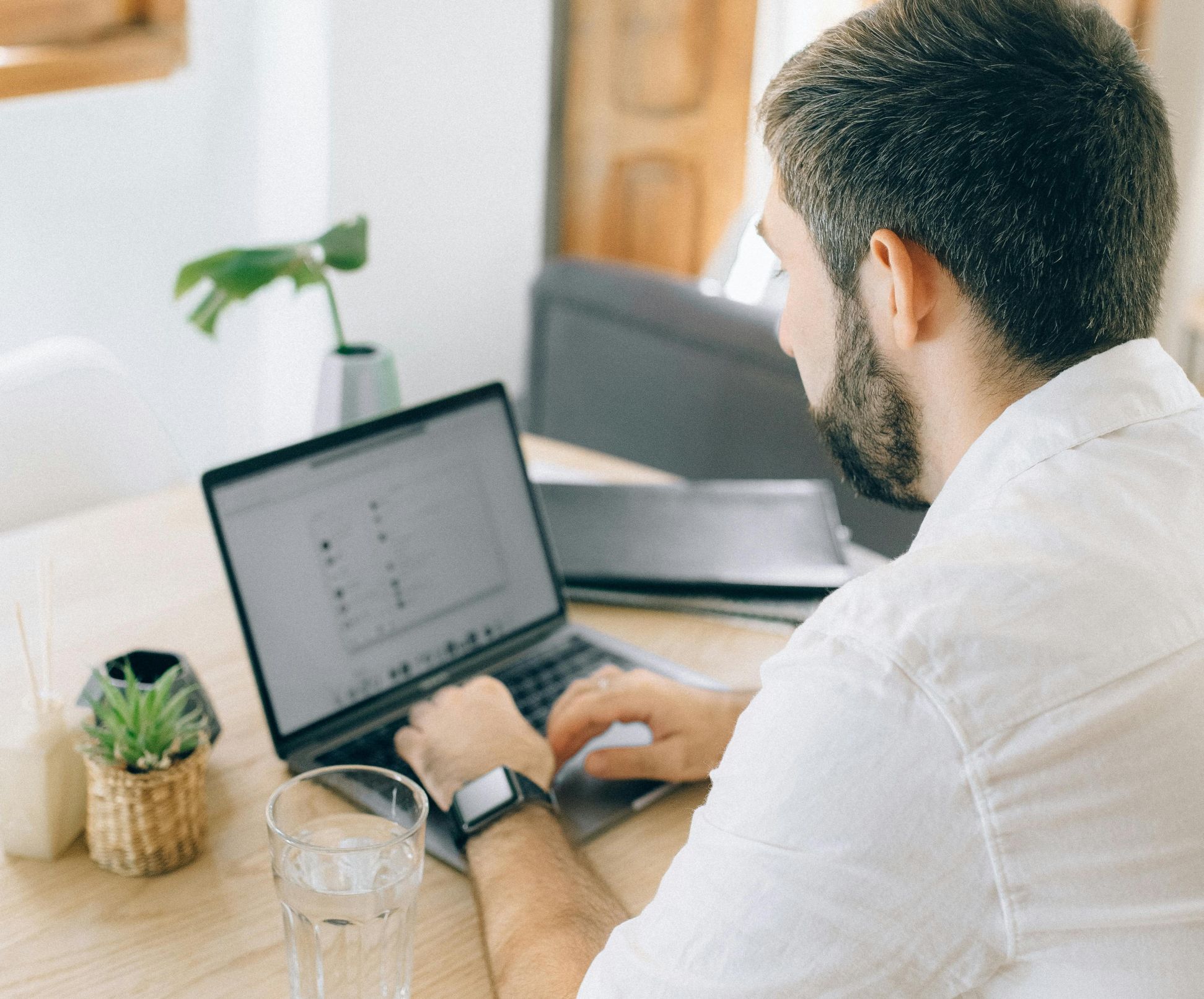 Online therapy reviews, how to ask for a review, how to ask for a google review, image of a man sitting at a table typing on his laptop.