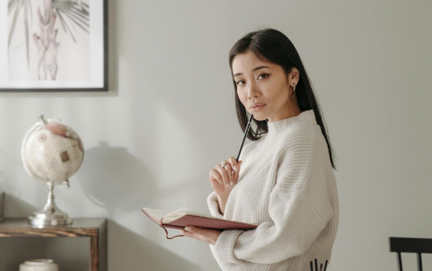 email testing , throwaway emails, image of a woman holding a notebook and pen thinking.