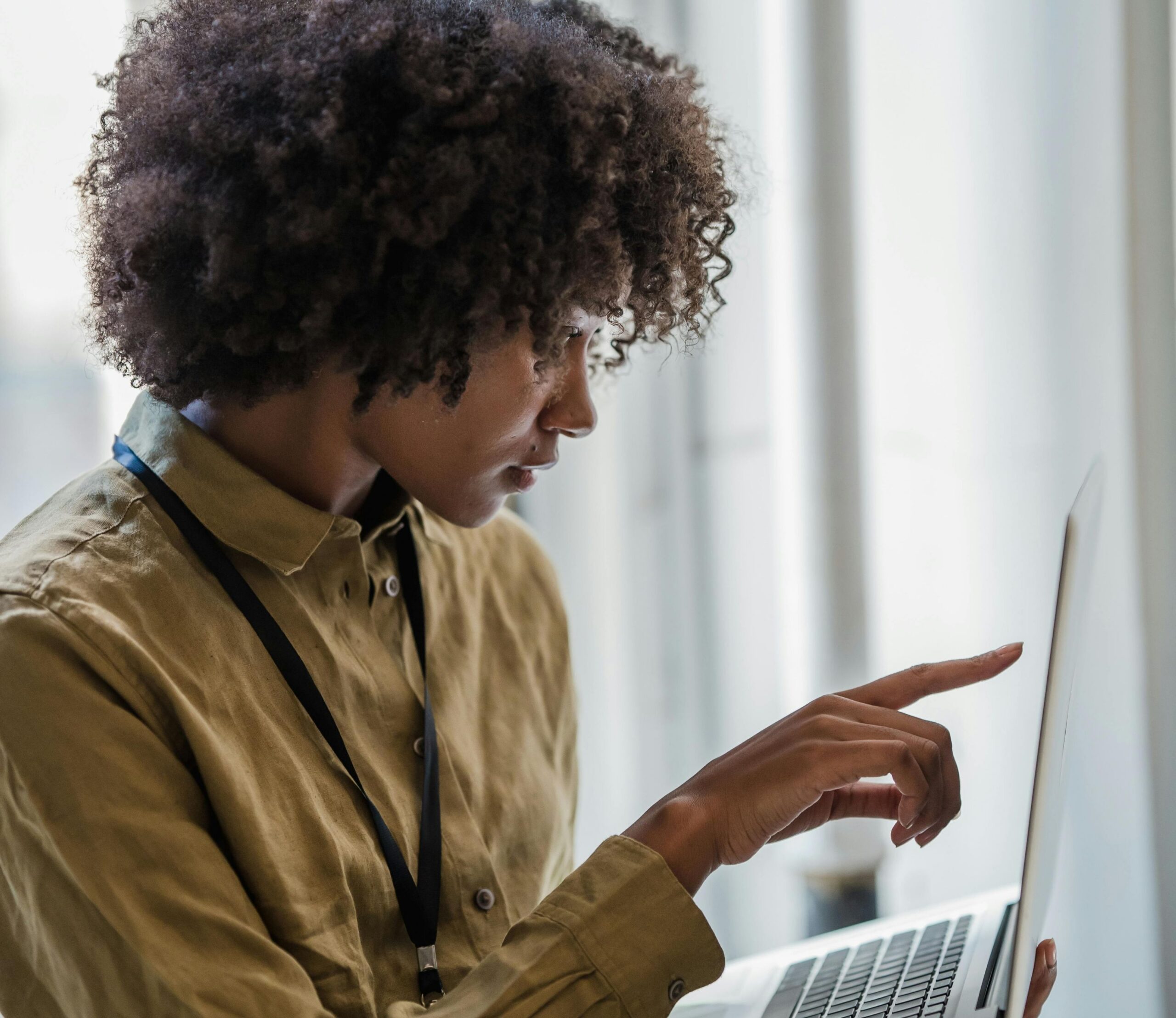 Image of a professional woman pointing at her laptop screen.