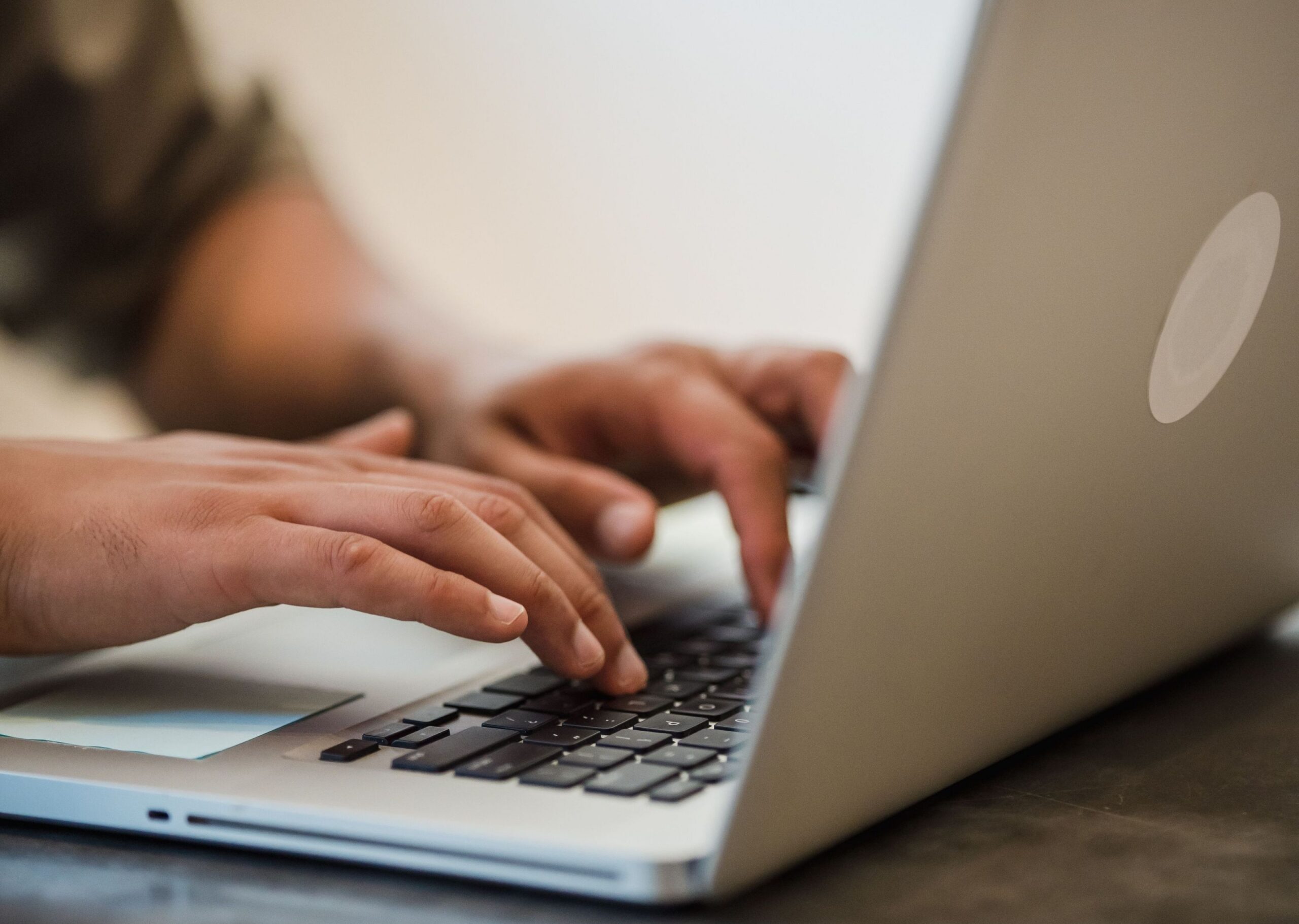 A person’s hands type on the keyboard of a laptop.
