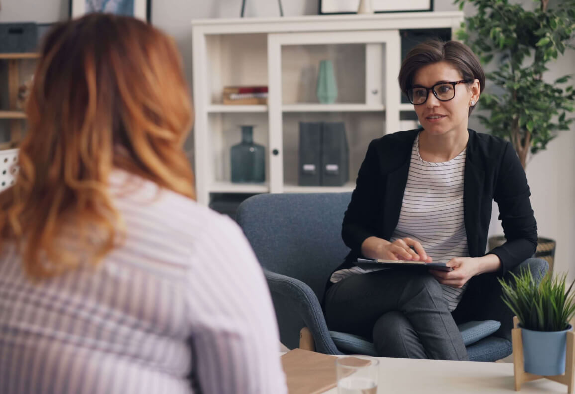 Therapist looks at and actively listens to a client sitting across from them.