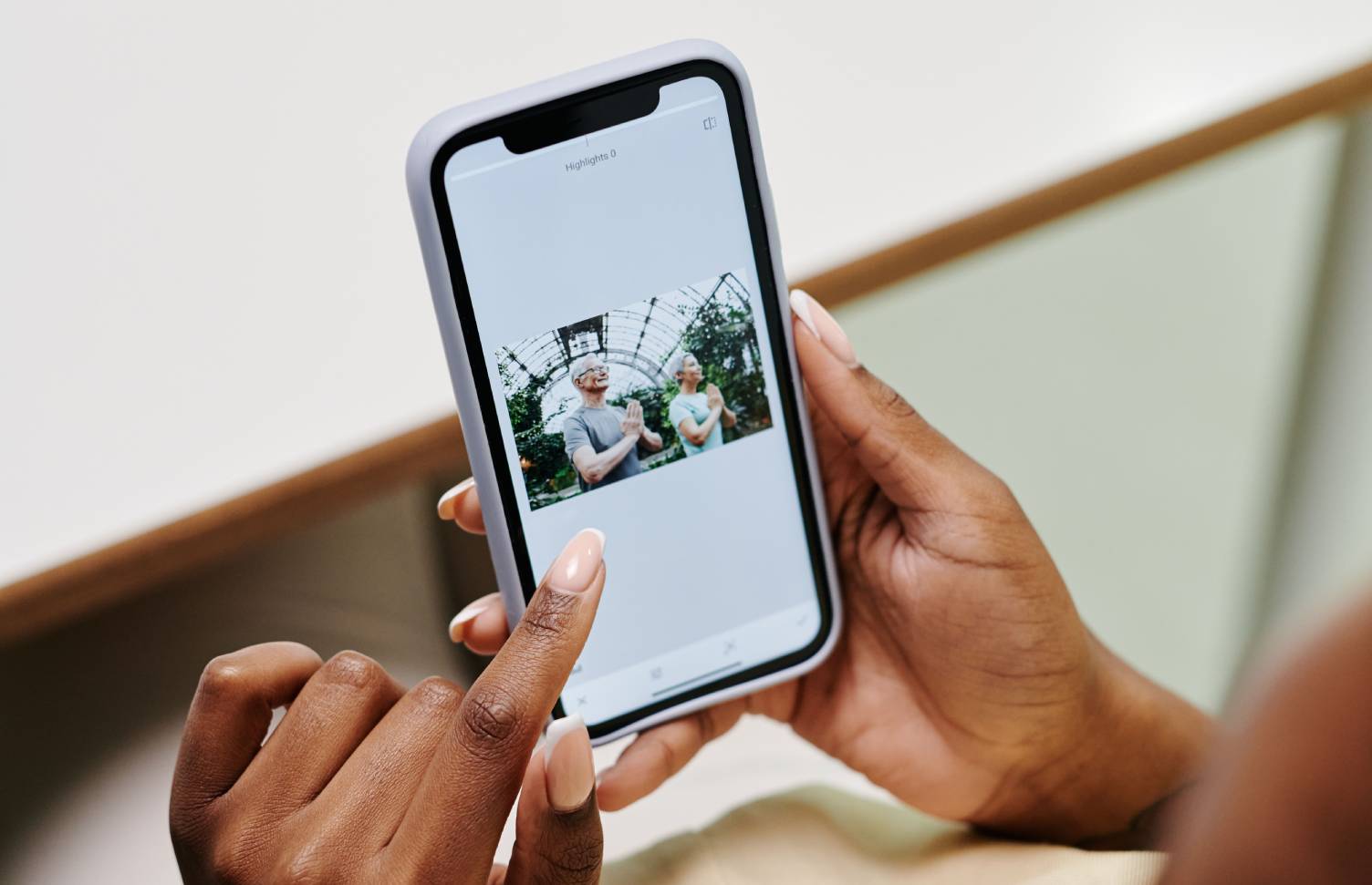 A woman holds her cellphone and looks at a free wellness resource on the screen.