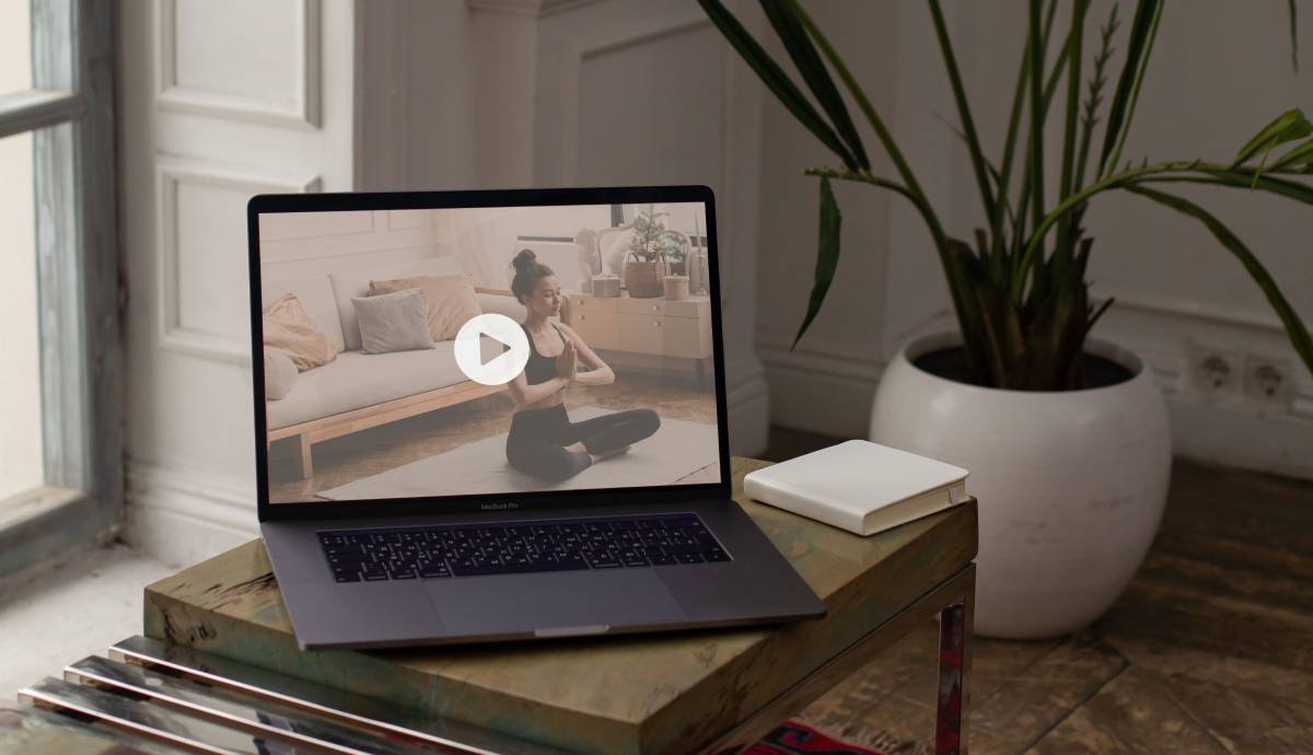 a laptop on a coffee table with a yoga video on the screen