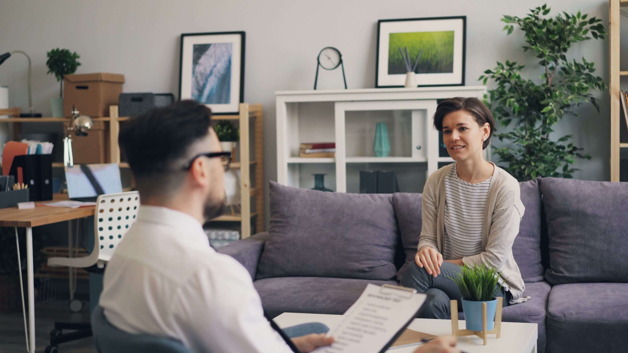 Image of a therapist sitting in a chair across from a client sitting on a sofa.